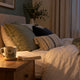 Calm bedroom with a book and warm drink prepared for a repeatable wind-down routine
